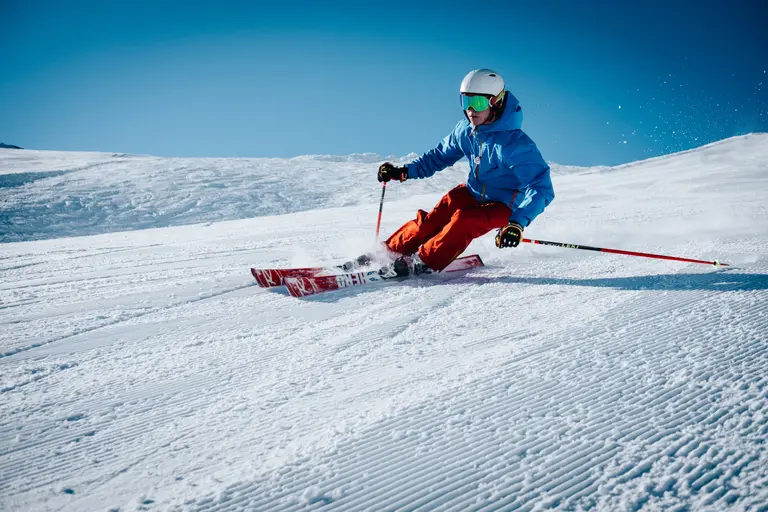Ein Skifahrer mit roter Hose und blaue Skijacke fährt am Silvester eine Piste in den österreichischen Alpen