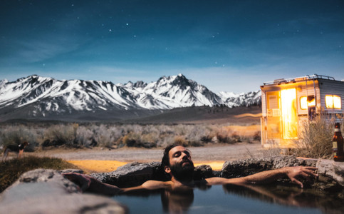 Mann entspannt im Wasser vor Bergkulisse